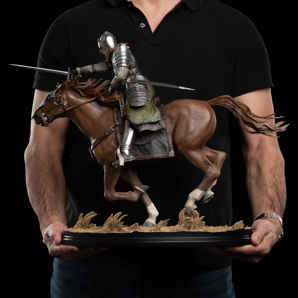 Un membre de l'équipe Wētā tient la statue de Faramir à deux mains pour montrer sa taille