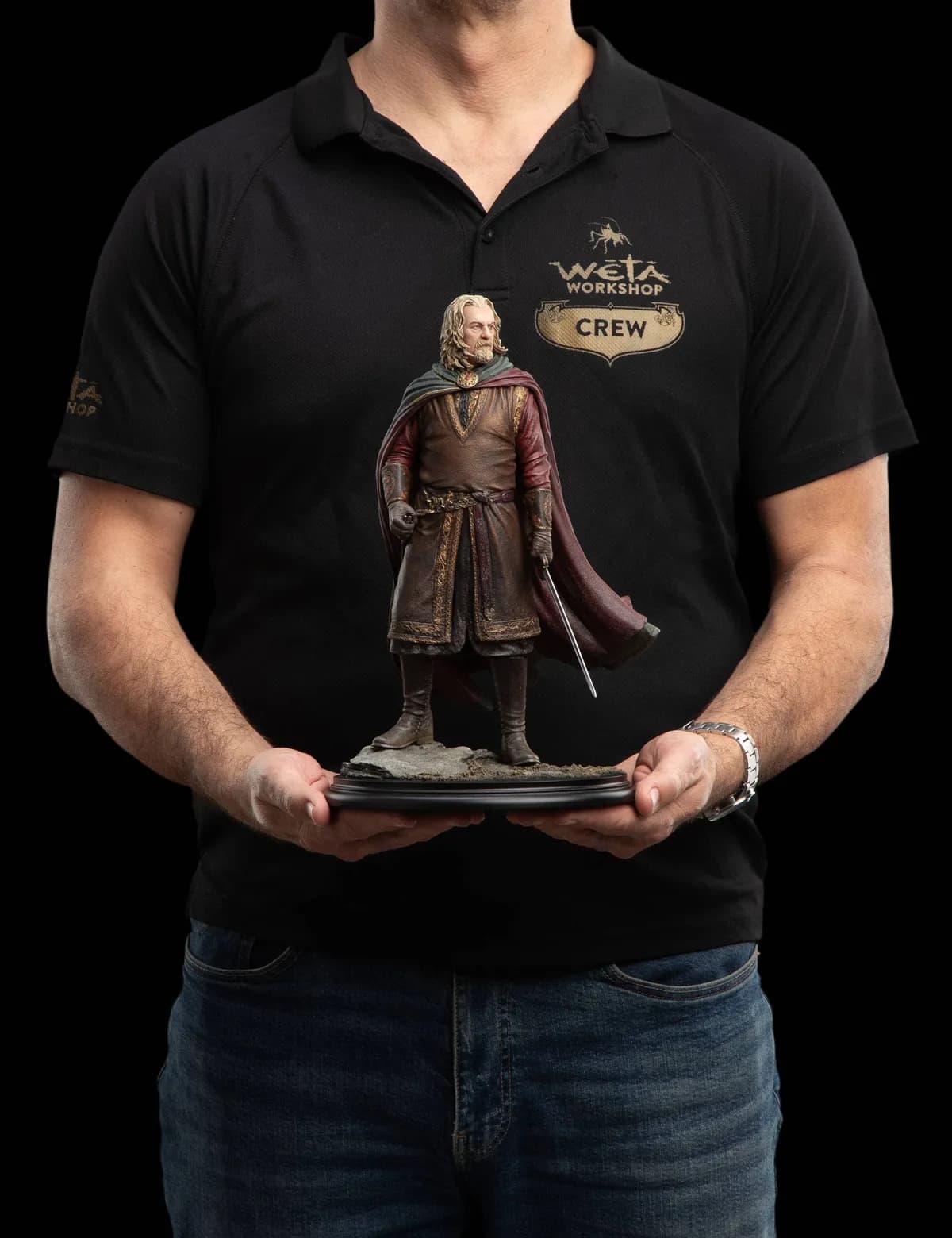 Un membre de l'équipe Wētā Workshop tient la statue de Théoden pour montrer sa taille