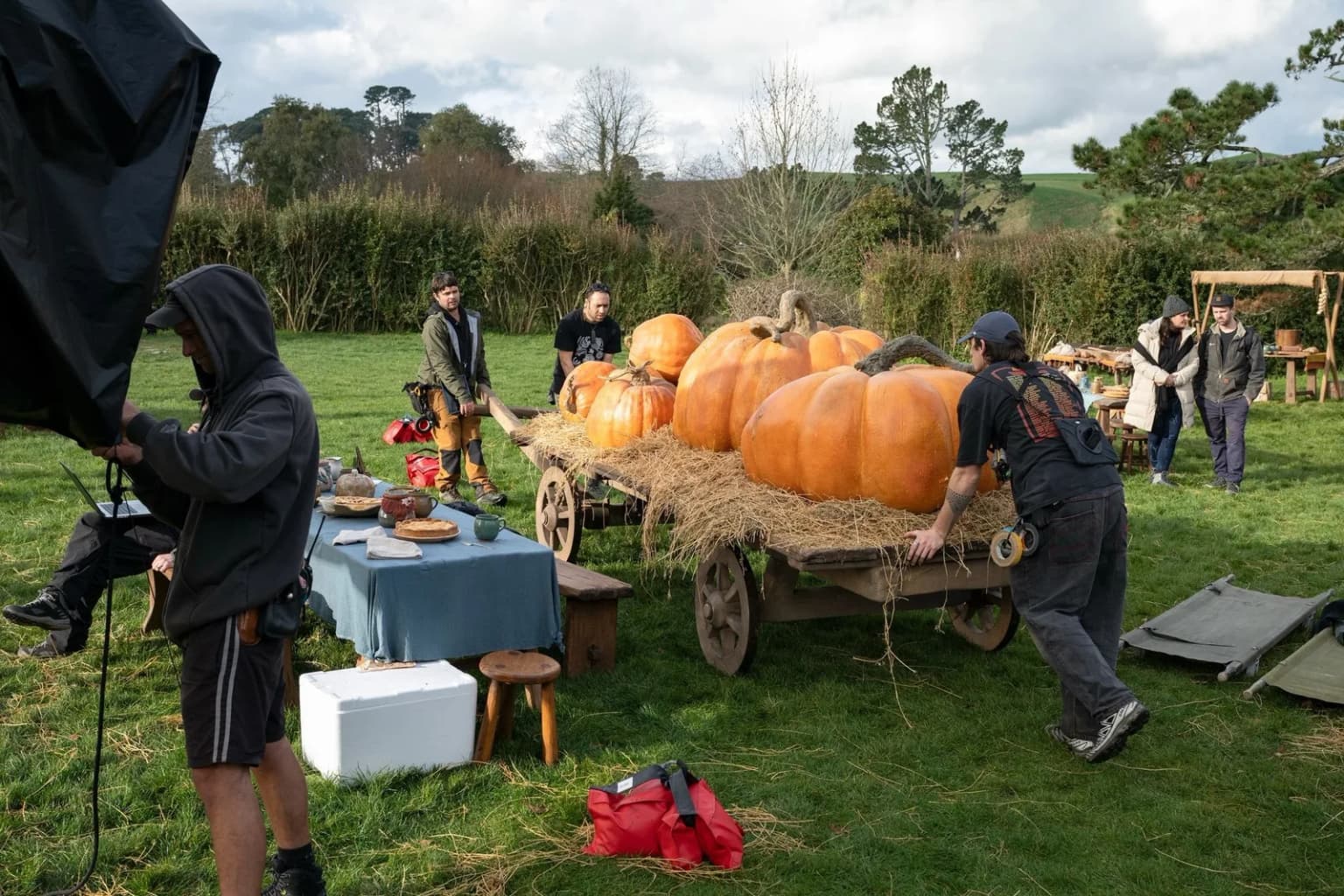 Des membres de l'équipe technique installent une charrette de citrouilles pour une scène de fête des récoltes